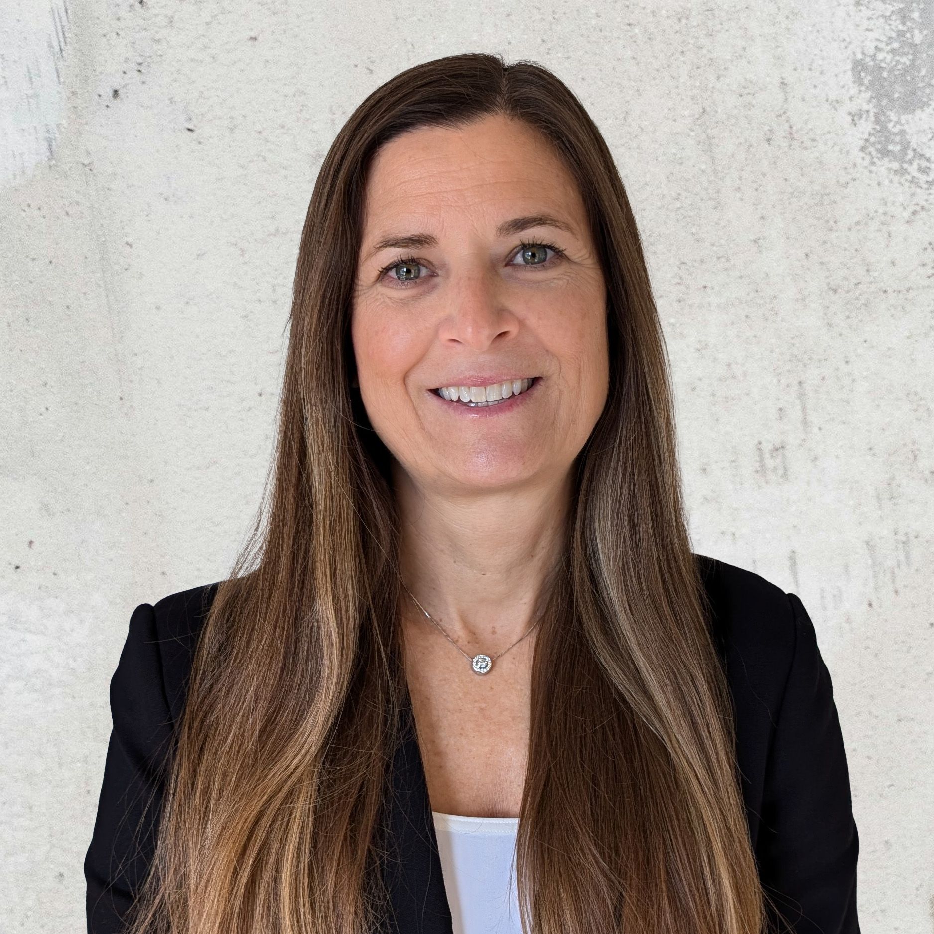 Headshot of Elise Crocker, Director of Project Quality and Partner Advocacy, wearing a black blazer and white top, smiling warmly against a light textured background.